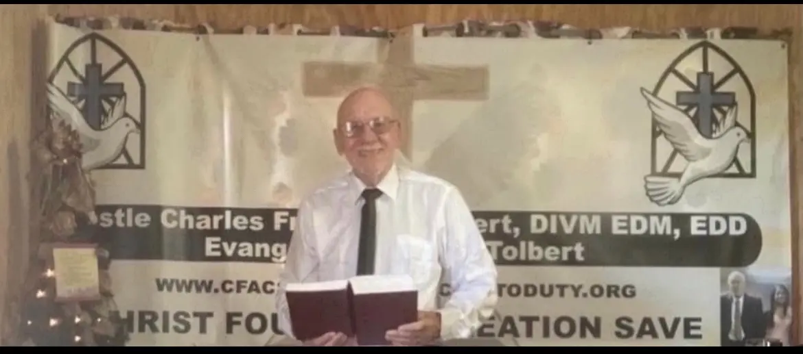 A man holding a book in front of a cross.