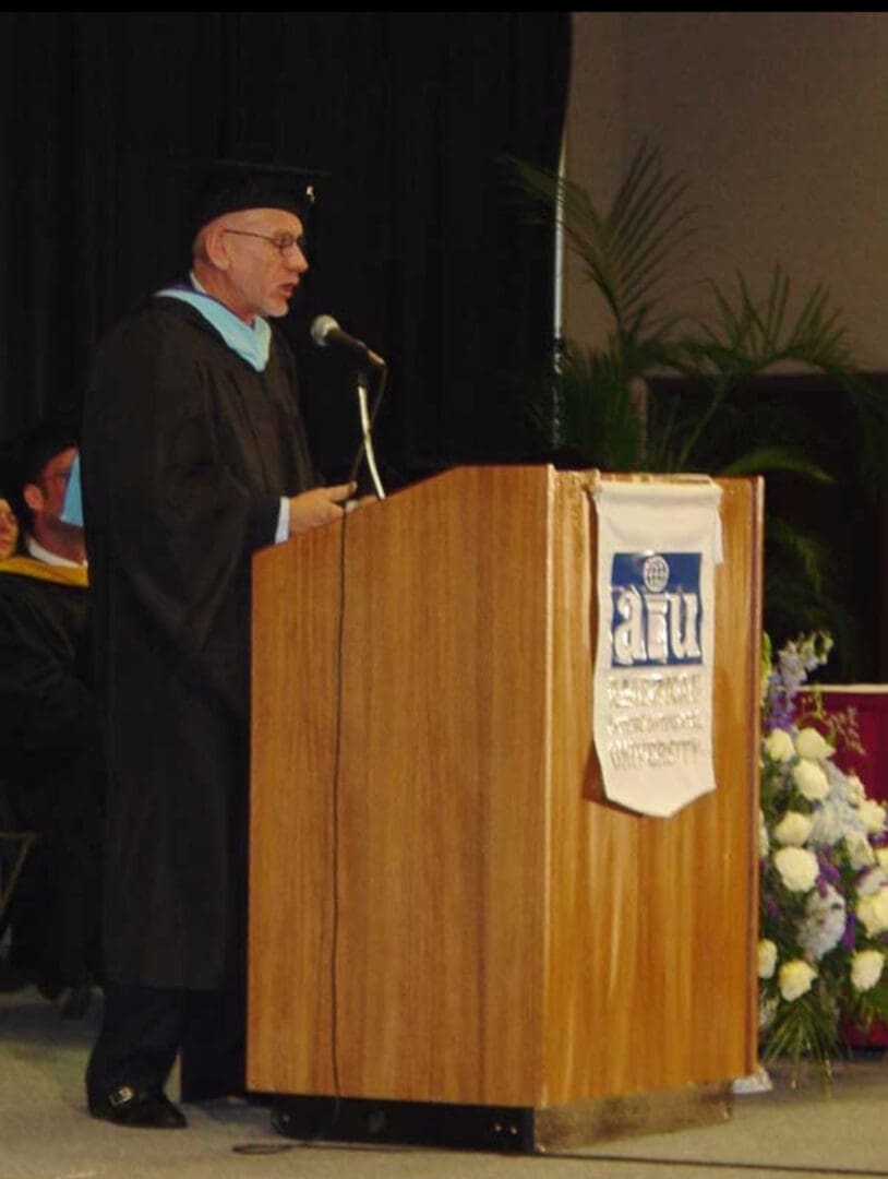 A man in graduation cap and gown standing at the podium.